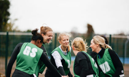 Female netball team shaking hands on netball court